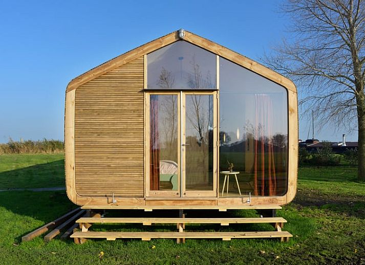 Ferienhaus in Broek in der friesischen Landschaft, modernes Holzhaus mit grosser Glasfassade und Aussicht auf die gruene Umgebung.