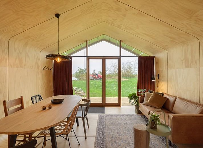 Ferienhaus in Broek in der friesischen Landschaft, modernes Holzhaus mit grosser Glasfassade und Aussicht auf die gruene Umgebung.