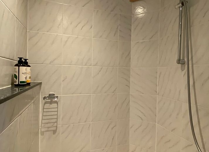 Uitzicht vanuit Vakantiehuis in De Hoeve over het Friese platteland, met moderne stoelen op het terras.