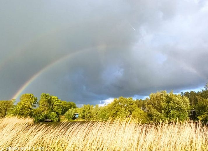 Dubbele regenboog boven Vakantiehuisje in Jislum, Friesland, omgeven door groene natuur.