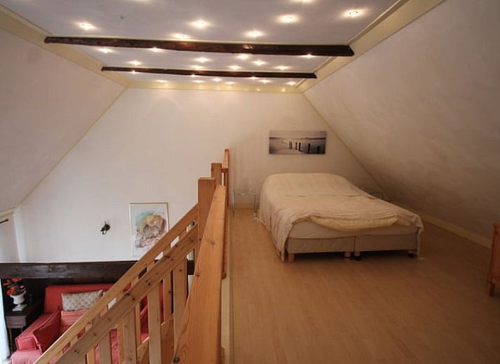 Gezellige binnenruimte van Huisje in Readtsjerk op het Friese platteland, met houten trap en knusse zithoek voor een ontspannen verblijf.