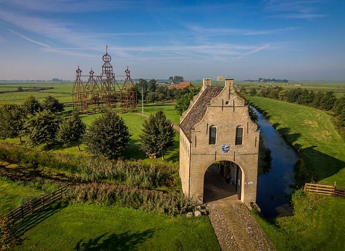 Rustieke omgeving van Huisje in Bears, vakantiehuis op het Friese platteland, met weelderige natuur en serene waterloop in Friesland.