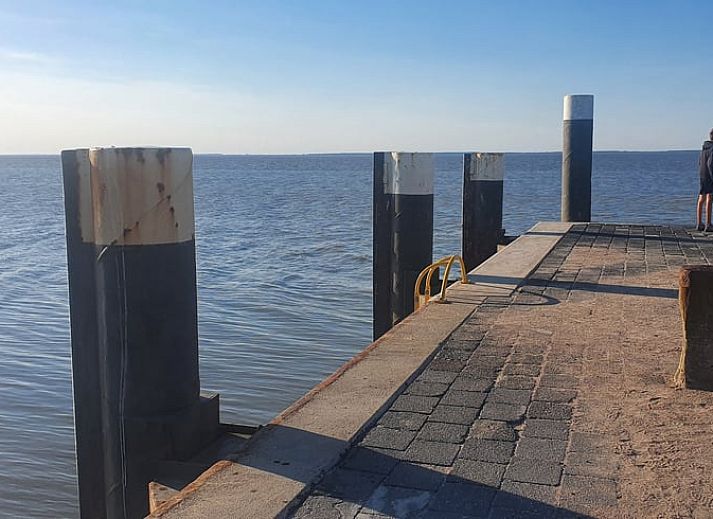 Schlafzimmer im Ferienhaus in Holwerd mit Blick auf die gruene Umgebung von Friesland.
