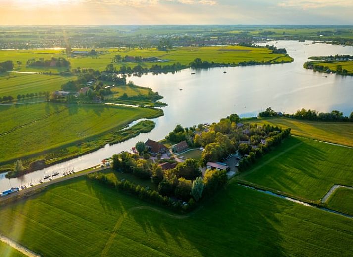 Overzicht van Huisje in Nes, Friesland, omgeven door groen en water voor een serene vakantie.