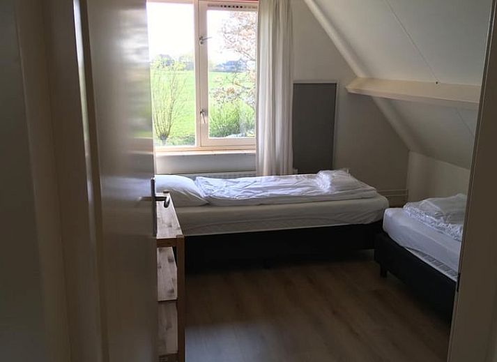 Gemuetliches Wohnzimmer mit Blick auf den Garten im Ferienhaus in Nes, Friesland, ideal zum Entspannen.