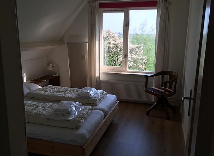 Gemuetliches Wohnzimmer mit Blick auf den Garten im Ferienhaus in Nes, Friesland, ideal zum Entspannen.