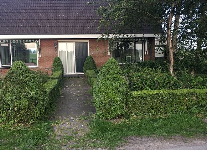 Gemuetliches Wohnzimmer mit Blick auf den Garten im Ferienhaus in Nes, Friesland, ideal zum Entspannen.