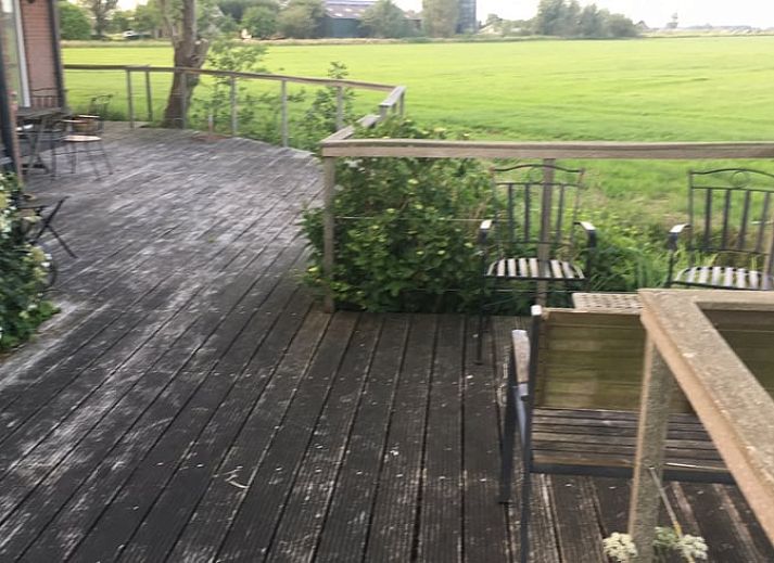 Gemuetliches Wohnzimmer mit Blick auf den Garten im Ferienhaus in Nes, Friesland, ideal zum Entspannen.