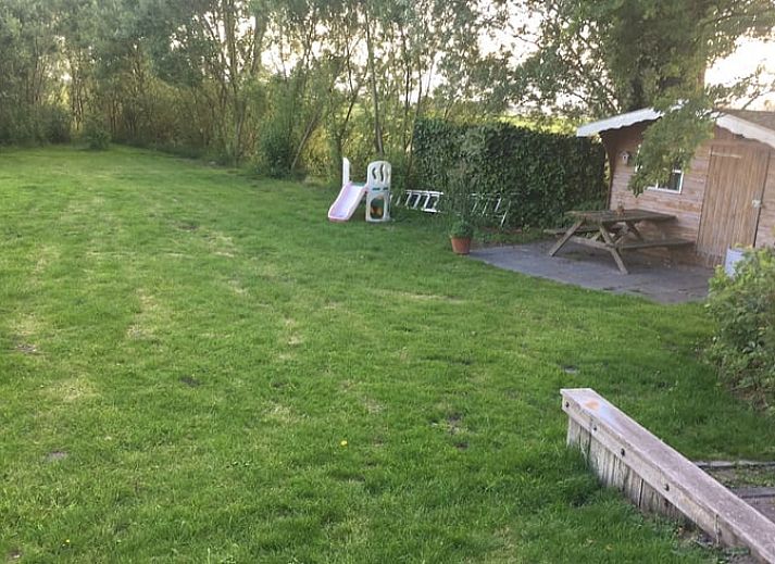 Gemuetliches Wohnzimmer mit Blick auf den Garten im Ferienhaus in Nes, Friesland, ideal zum Entspannen.