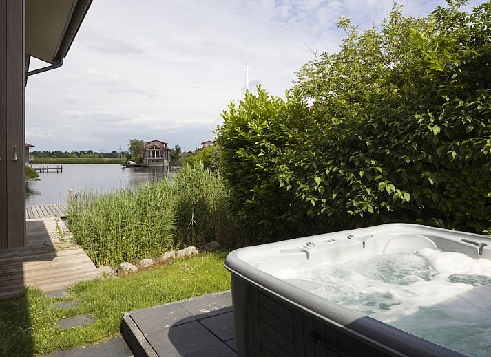 Ruime woonkamer in Goudplevier Bubbelbad 10+2, een bungalow in Noardburgum, Friesland, met uitzicht op het Friese platteland en water.