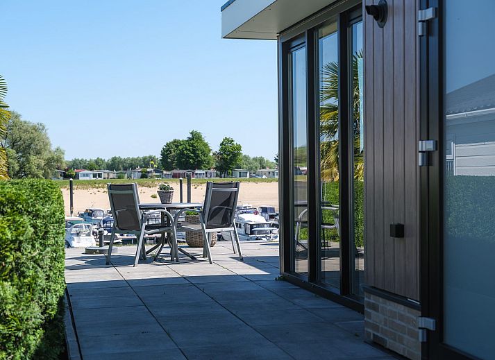 Geniessen Sie die Terrasse von Cube XL mit Sauna, einem modernen Ferienhaus fuer 4 Personen in Lathum, Gelderland, umgeben von Natur.
