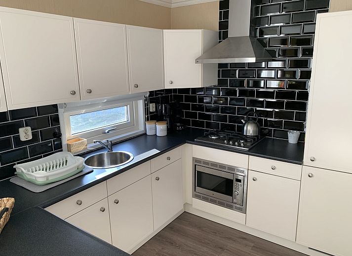 Enjoy the sun on the terrace of Zand Lodge in Lathum, Gelderland, with comfortable deck chairs and a cozy seating area for six.