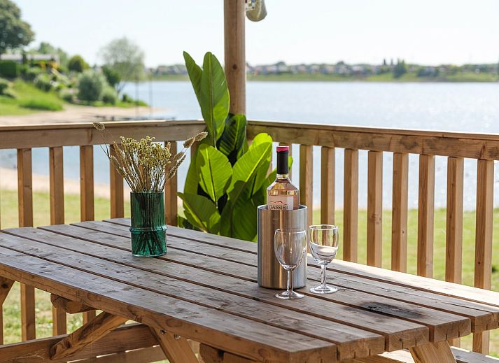 Terras van Safaritent Ranger in Lathum, Gelderland, met comfortabele zitplaatsen en uitzicht op de rivier.