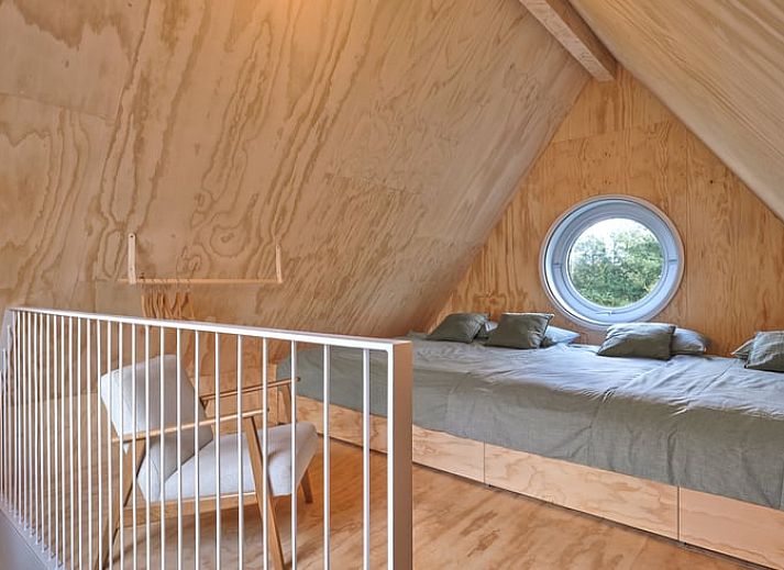 Innenraum eines Ferienhauses in Arnheim mit grossem Rundfenster und Blick in die Natur.