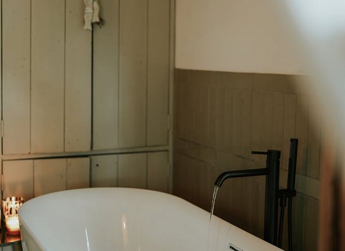Attractive bathroom in Holiday Home in Altforst, Gelderland, with freestanding bathtub and rustic wooden elements for a relaxing stay.