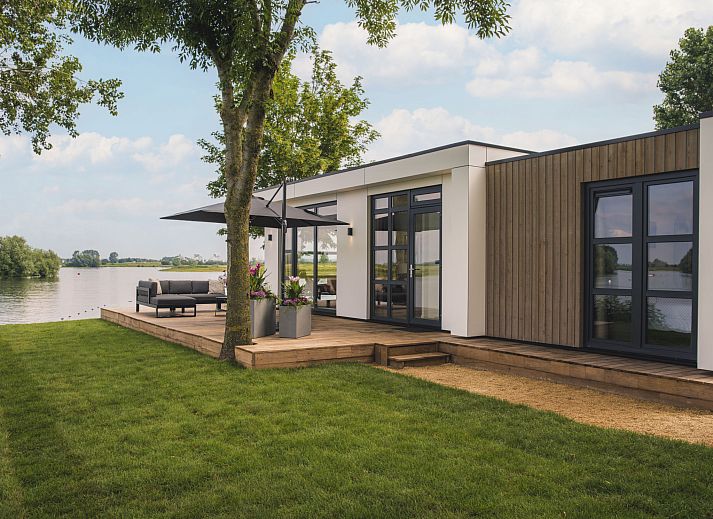 Terrasse mit bequemem Loungesofa im Ferienhaus MarinaPark Bad Nederrijn in Maurik, Gelderland mit Blick auf den Fluss.