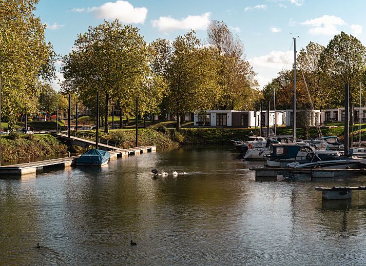 Gemuetliches Wohnzimmer im Ferienhaus MarinaPark Bad Nederrijn, Maurik, Gelderland mit Flussblick und moderner Einrichtung.