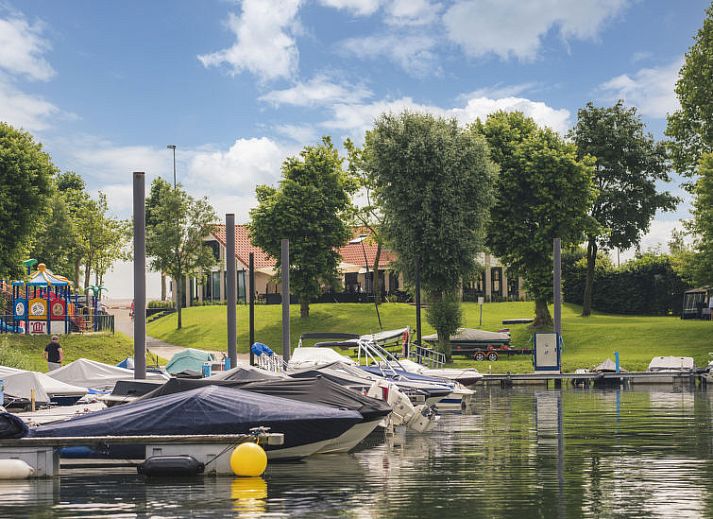 Veranda met ligstoelen bij Vakantiehuis MarinaPark Bad Nederrijn in Maurik, Gelderland met uitzicht op het water.