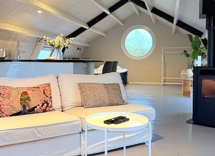 Gezellige binnenruimte van Huisje in Acquoy, vakantiehuis in Rivierengebied, Gelderland, met comfortabele bank en sfeervolle houtkachel.