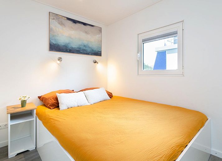 La Serafat Ferienhaus in Maasbommel, Gelderland, schwimmend auf dem Wasser mit Dachterrasse und Sonnenschirm.