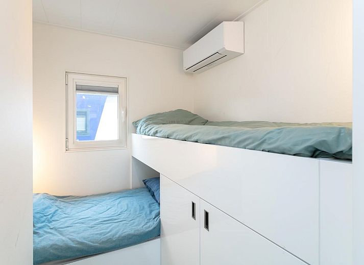 La Serafat Ferienhaus in Maasbommel, Gelderland, schwimmend auf dem Wasser mit Dachterrasse und Sonnenschirm.