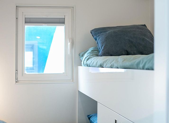 La Serafat Ferienhaus in Maasbommel, Gelderland, schwimmend auf dem Wasser mit Dachterrasse und Sonnenschirm.