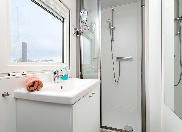 La Serafat Ferienhaus in Maasbommel, Gelderland, schwimmend auf dem Wasser mit Dachterrasse und Sonnenschirm.