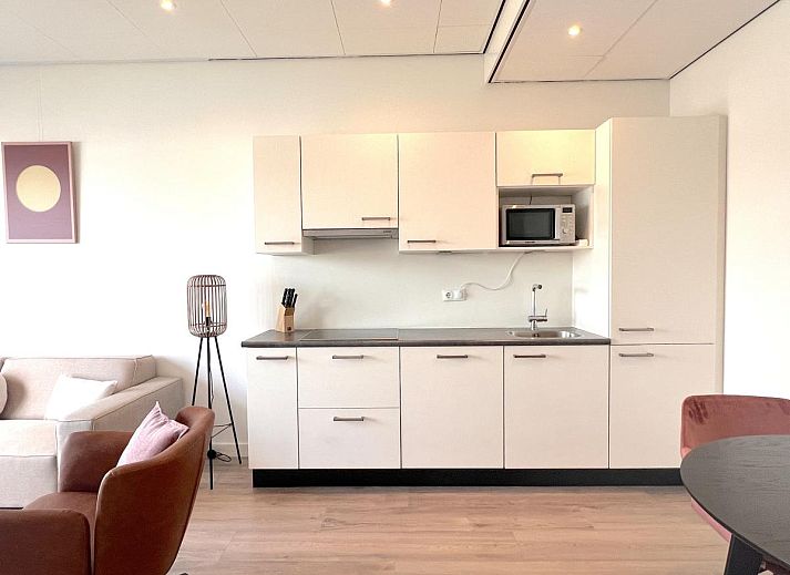 Essecke im Ferienhaus Havenzicht, Maasbommel, mit eleganten rosafarbenen Stuehlen und Blumenschmuck im Rivierengebied, Gelderland.