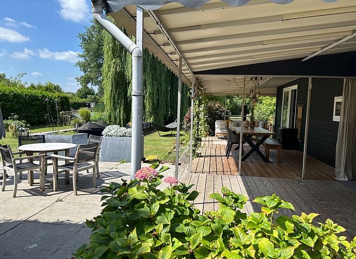 Geniet van de veranda van Huisje in Gellicum, een vakantiehuis in het Rivierengebied van Gelderland, omringd door groen en rust.