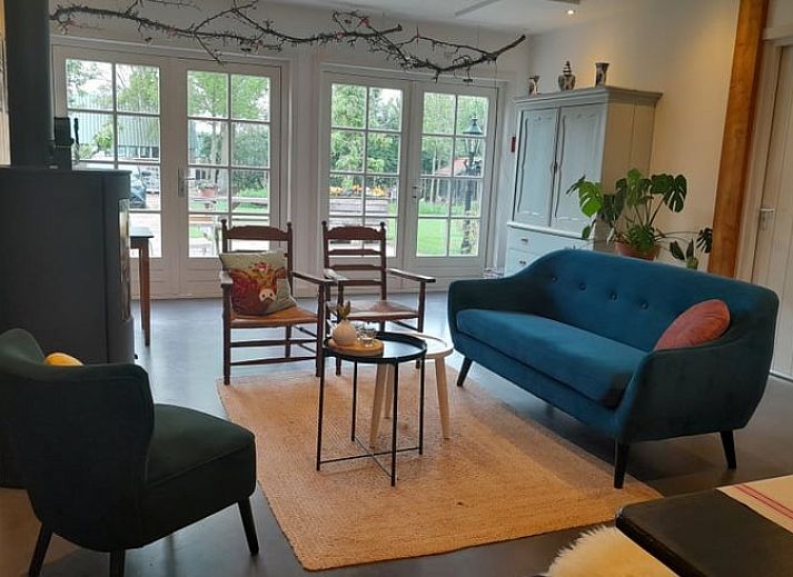 Cozy sitting area in Huisje in Westendorp, bed and breakfast in the Achterhoek, with wooden chairs and views of greenery.