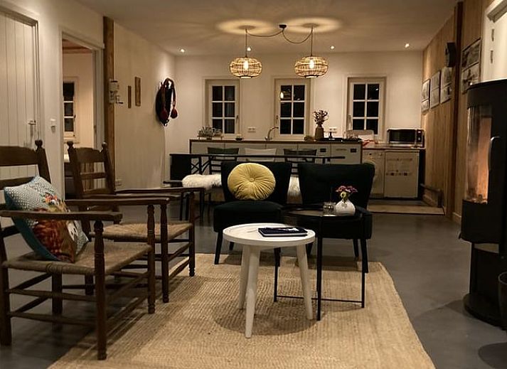 Cozy sitting area in Huisje in Westendorp, bed and breakfast in the Achterhoek, with wooden chairs and views of greenery.