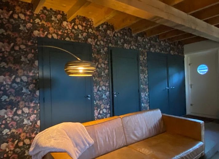 Gemuetliches Wohnzimmer des Ferienhauses in Laren, Achterhoek, Gelderland mit Blick auf den Garten und warmen Holzakzenten.