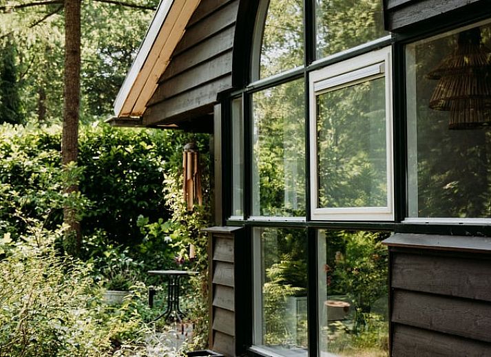Lichte zithoek in vakantiehuis in Lochem met uitzicht op het groene bos.