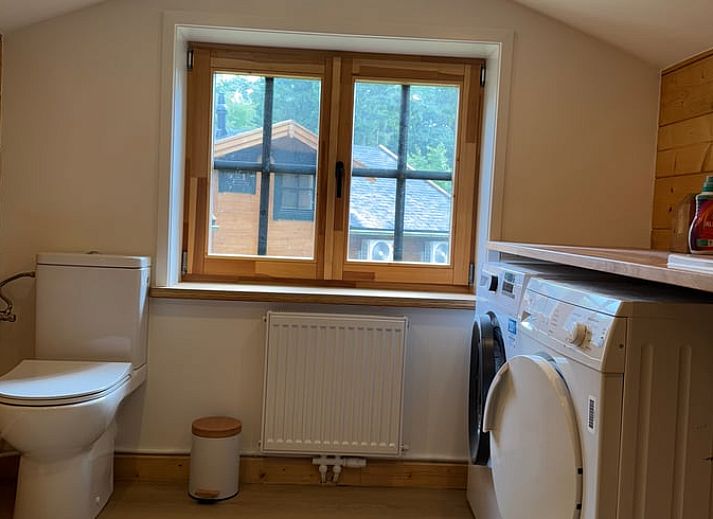 Gezellige woonkamer van Vakantiehuis in Lochem, Achterhoek, Gelderland met houten balken, ruime zithoek en uitzicht op groene tuin.