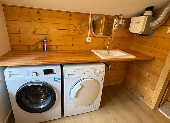 Gezellige woonkamer van Vakantiehuis in Lochem, Achterhoek, Gelderland met houten balken, ruime zithoek en uitzicht op groene tuin.