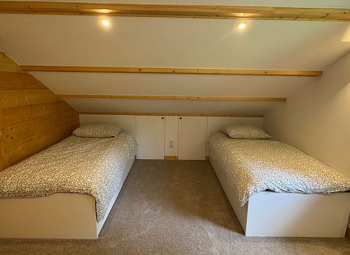 Gezellige woonkamer van Vakantiehuis in Lochem, Achterhoek, Gelderland met houten balken, ruime zithoek en uitzicht op groene tuin.