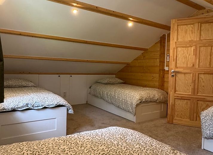 Gezellige woonkamer van Vakantiehuis in Lochem, Achterhoek, Gelderland met houten balken, ruime zithoek en uitzicht op groene tuin.