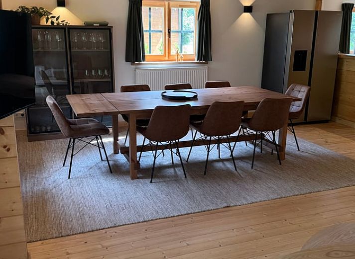 Gezellige eetkamer in Vakantiehuis in Lochem, Achterhoek, met houten tafel en uitzicht op groene tuin, ideaal voor ontspannen verblijf in Gelderland.
