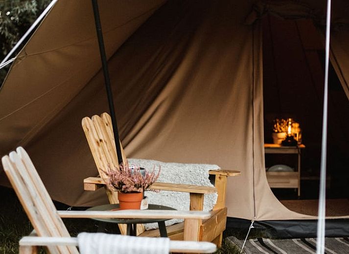 Gezellige veranda bij Vakantiehuisje in Haarlo, Achterhoek, Gelderland met houten stoelen en sfeervolle verlichting.