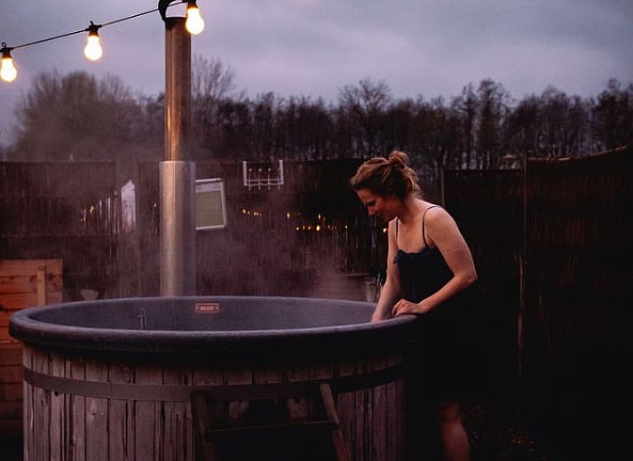 Gezellige veranda bij Vakantiehuisje in Haarlo, Achterhoek, Gelderland met houten stoelen en sfeervolle verlichting.
