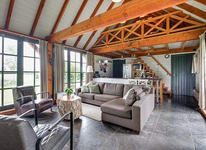 Ferienhaus in Zutphen mit Holzveranda in Achterhoek, Gelderland, umgeben von bunten Blumen.