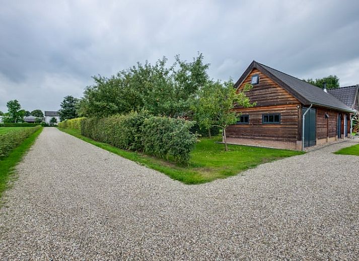 Ferienhaus in Zutphen mit Holzveranda in Achterhoek, Gelderland, umgeben von bunten Blumen.