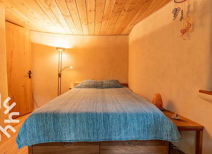 Schlafzimmer des Ferienhauses DG1417 in Neede, Achterhoek mit Holzdecke und Blick auf die gruene Umgebung.