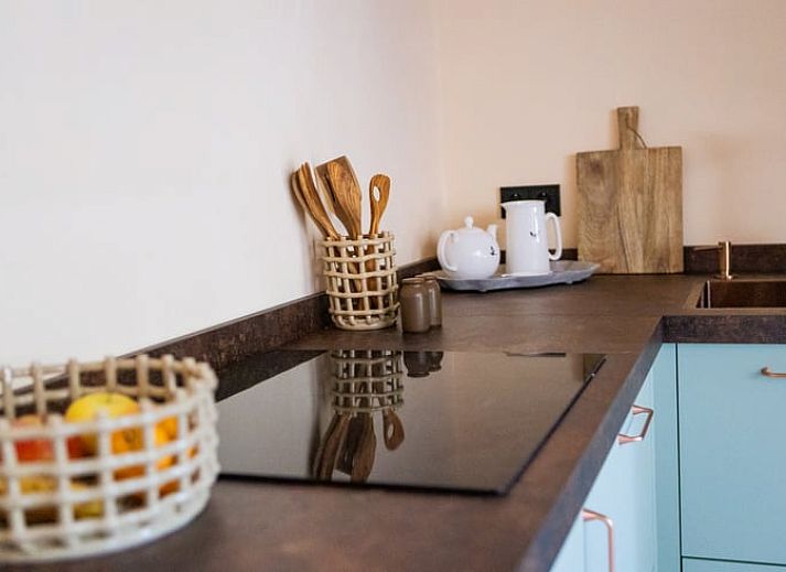 Gezellige woonkamer in Vakantiehuisje in Neede, Achterhoek, met moderne keuken en houten trap.