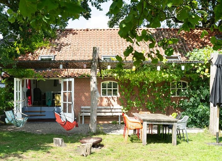 Geniessen Sie den gruenen Garten des Ferienhauses in Lievelde, Achterhoek, Gelderland. Entspannen Sie sich auf der Terrasse mit Haengematten und Sitzgelegenheiten.