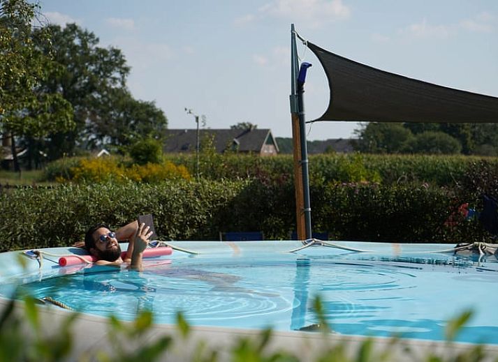 Geniessen Sie den gruenen Garten des Ferienhauses in Lievelde, Achterhoek, Gelderland. Entspannen Sie sich auf der Terrasse mit Haengematten und Sitzgelegenheiten.