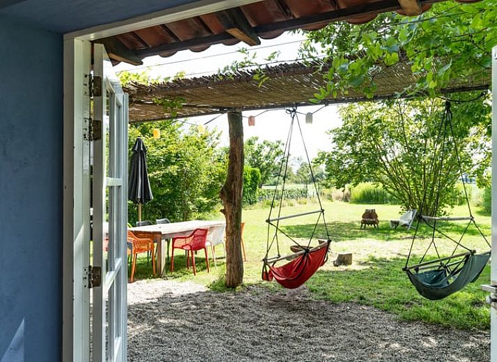 Geniessen Sie den gruenen Garten des Ferienhauses in Lievelde, Achterhoek, Gelderland. Entspannen Sie sich auf der Terrasse mit Haengematten und Sitzgelegenheiten.