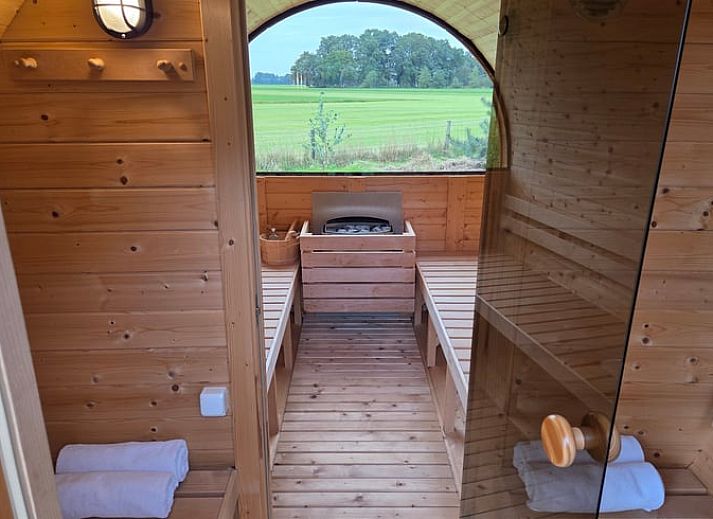 Geniessen Sie den gruenen Garten des Ferienhauses in Lievelde, Achterhoek, Gelderland. Entspannen Sie sich auf der Terrasse mit Haengematten und Sitzgelegenheiten.