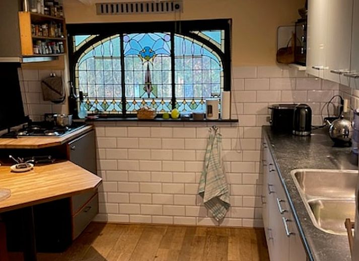 Gemuetliches Schlafzimmer im Ferienhaus in Joppe, Achterhoek, mit Holzmoebeln und Blick auf die gruene Natur durch grosse Fenster.