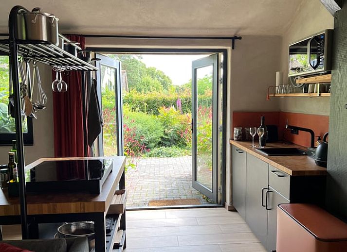 Charmant exterieur van Huisje in Empe, vakantieverblijf in Gelderland, omgeven door bomen.